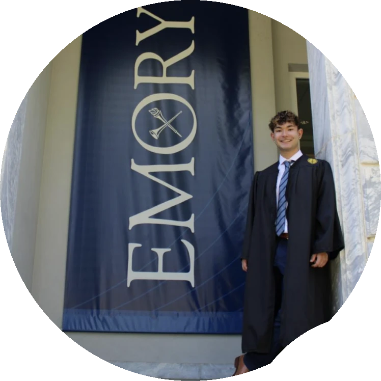 Jeremy in his Emory graduation gown in front of an Emory banner